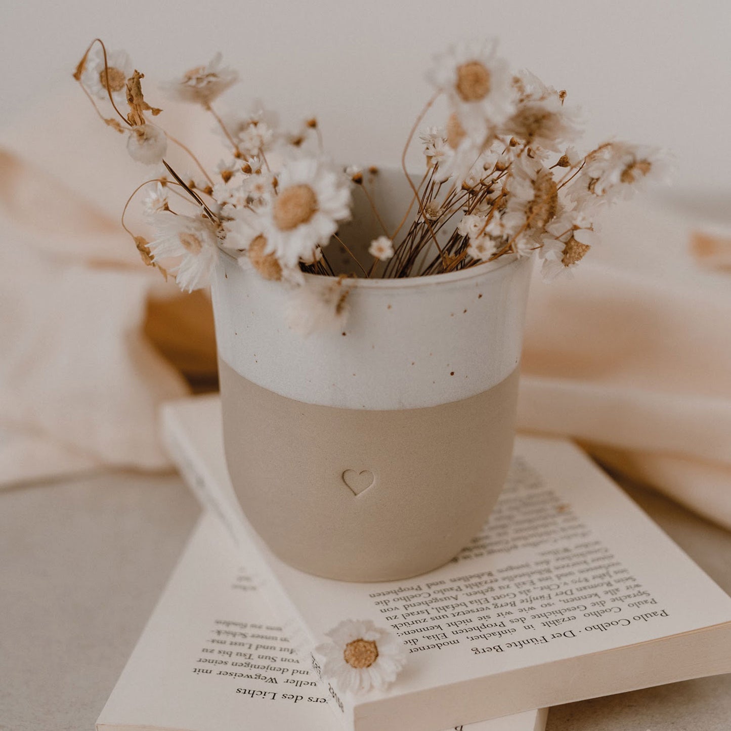 Becher Herz auf einem Buch mit Trockenblumen gefüllt