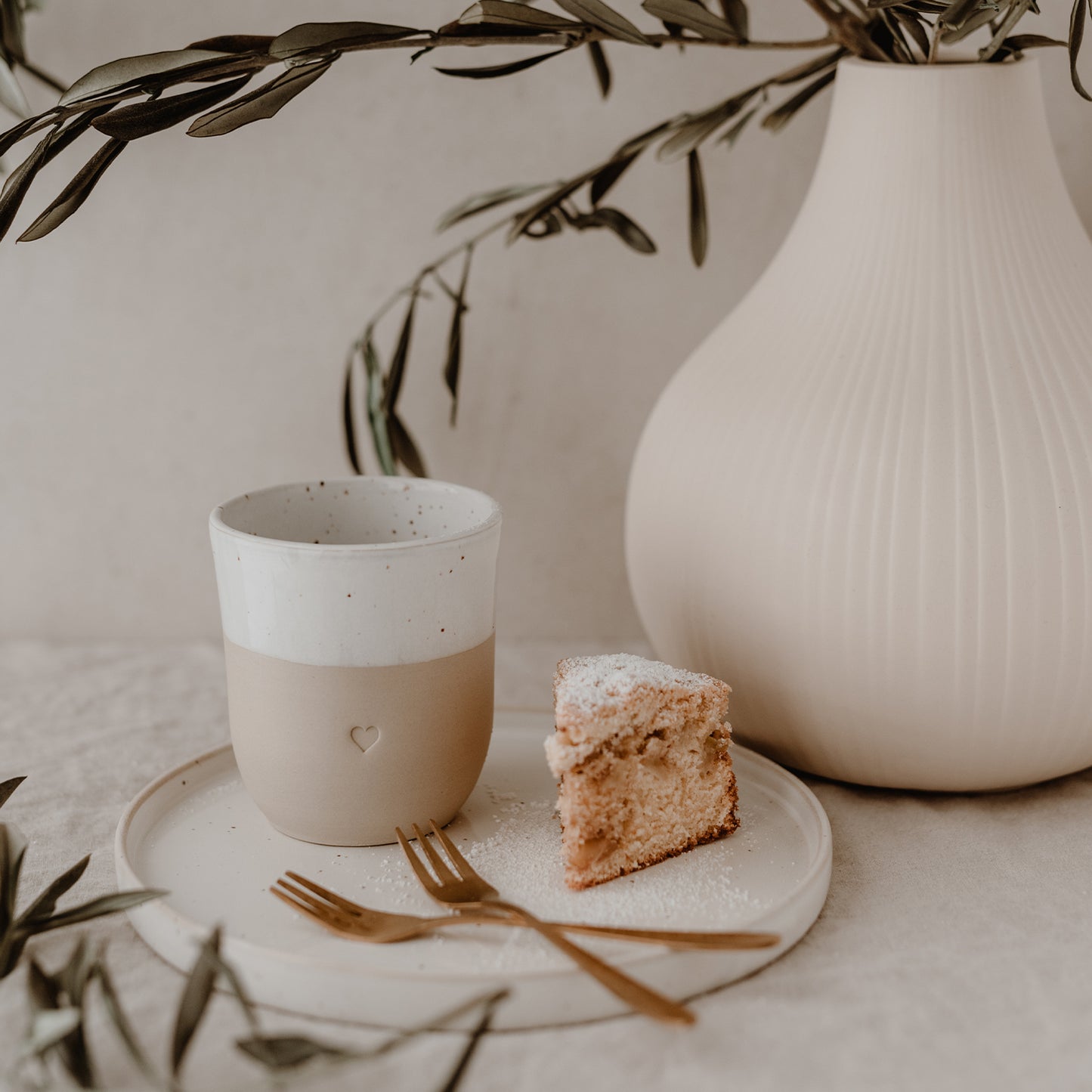 Becher Herz auf Teller neben Kuchen und Gabeln